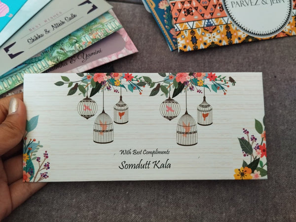 Card with birdcage design held by a hand on a textured surface