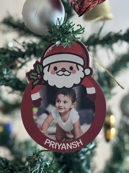 Christmas ornament with a child's photo and 'PRIYANSH' text on a tree.
