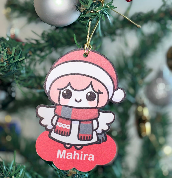 Christmas ornament with a cartoon character named Mahira hanging on a tree.