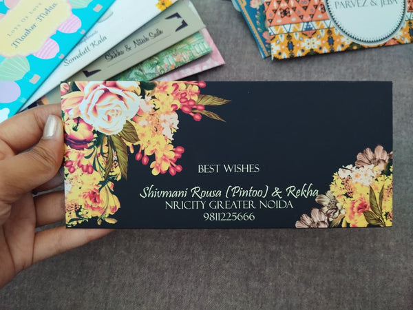 Floral design envelope held by a hand on a gray surface